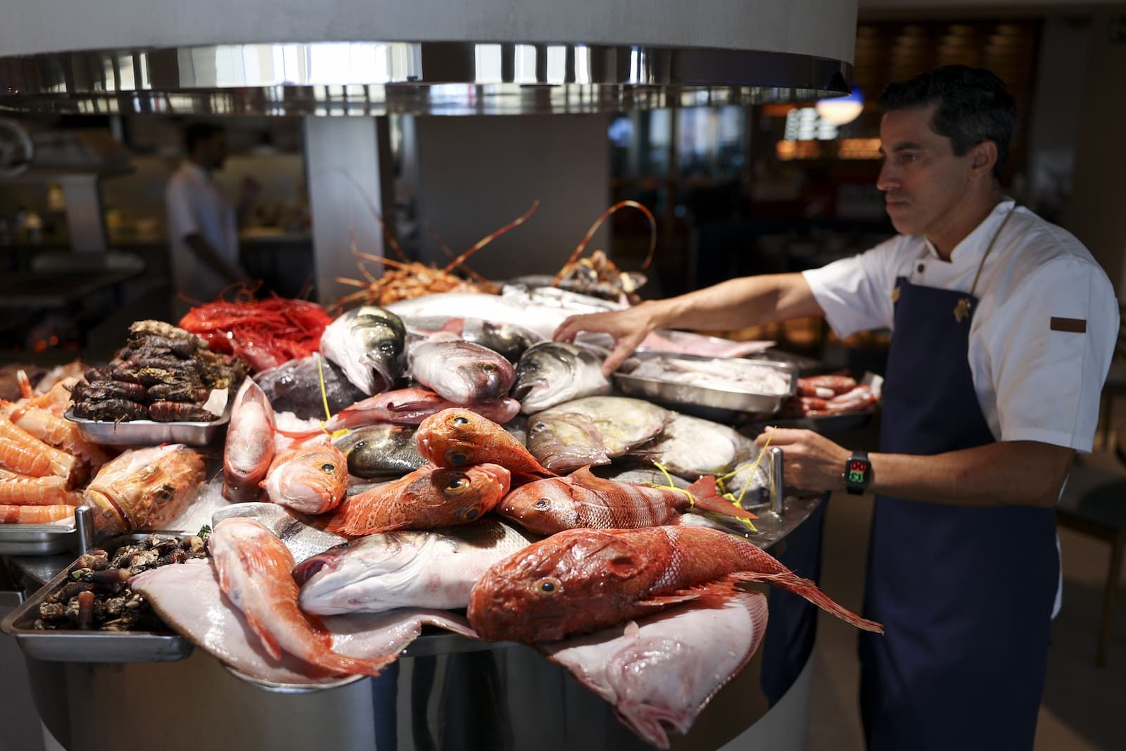 Un cocinero coloca el pescado del día en el expositor de Los Marinos José: gallinetas, lubinas, rodaballo, langostas y gambas rojas sobre hielo